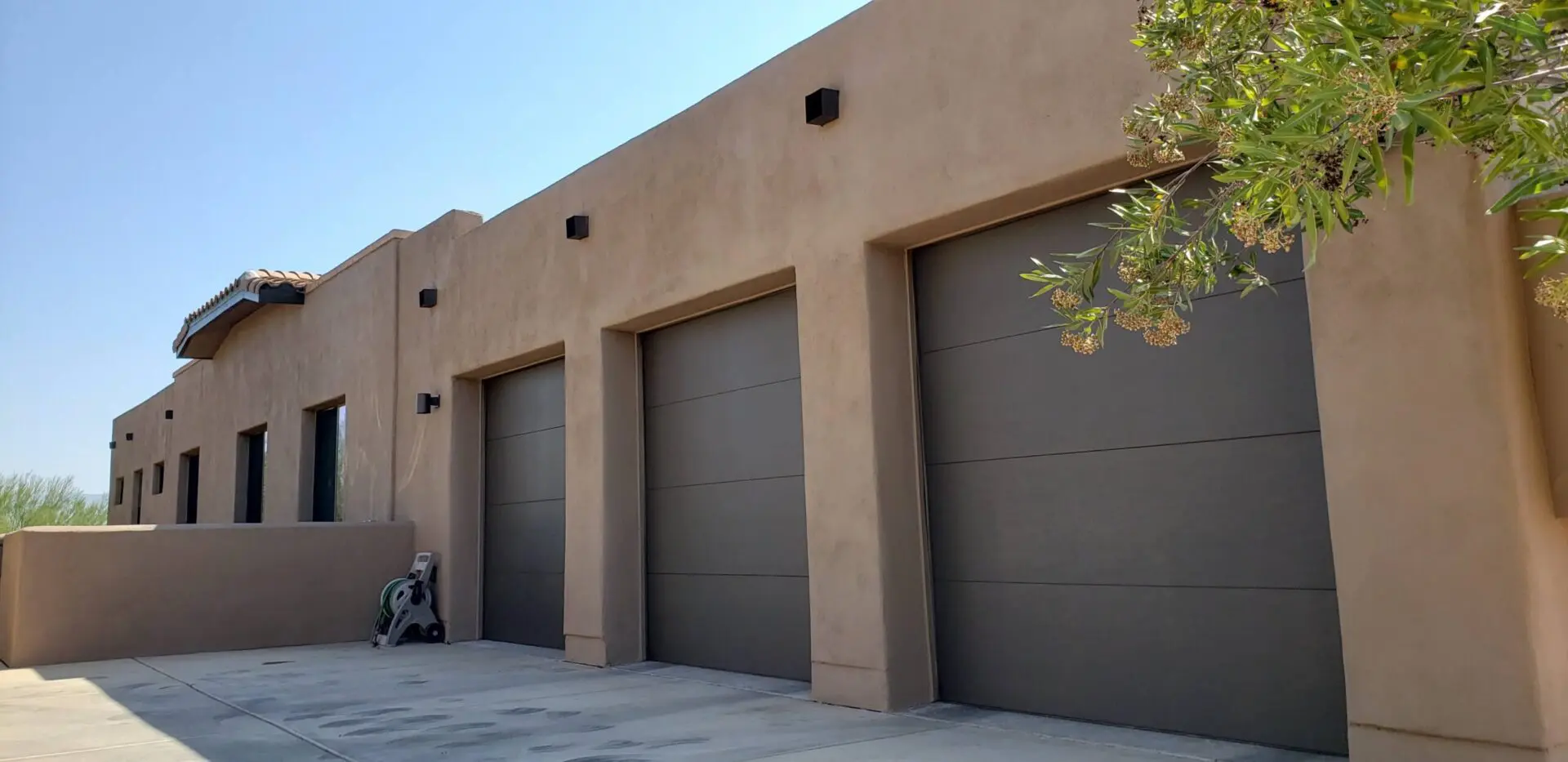 A row of three garage doors on the side of a building.