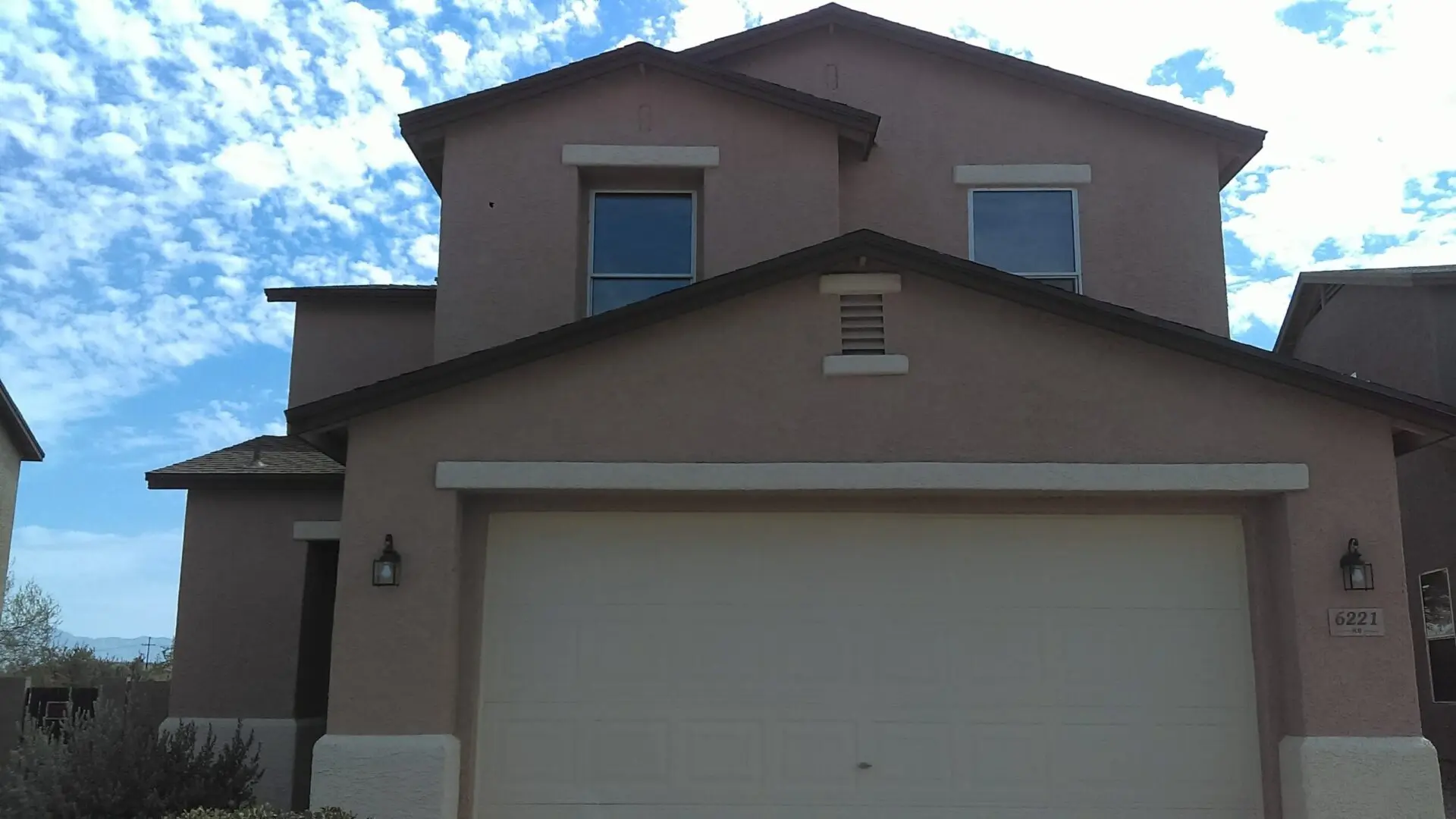 A house with two windows and a garage door.