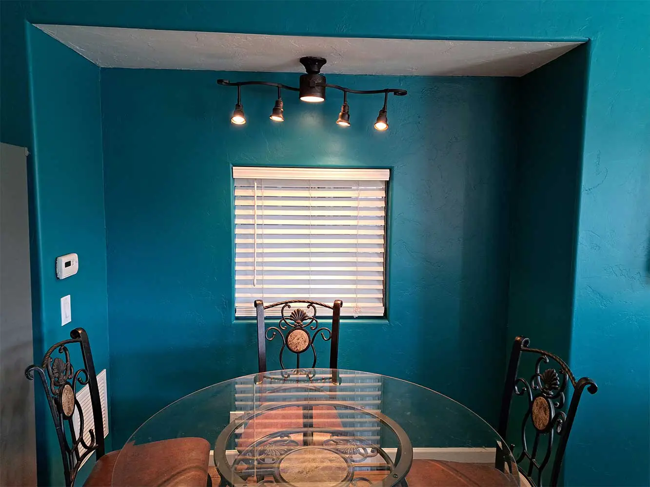 A dining room with blue walls and a glass table.