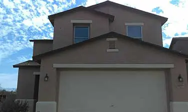 A house with two windows and a garage door.