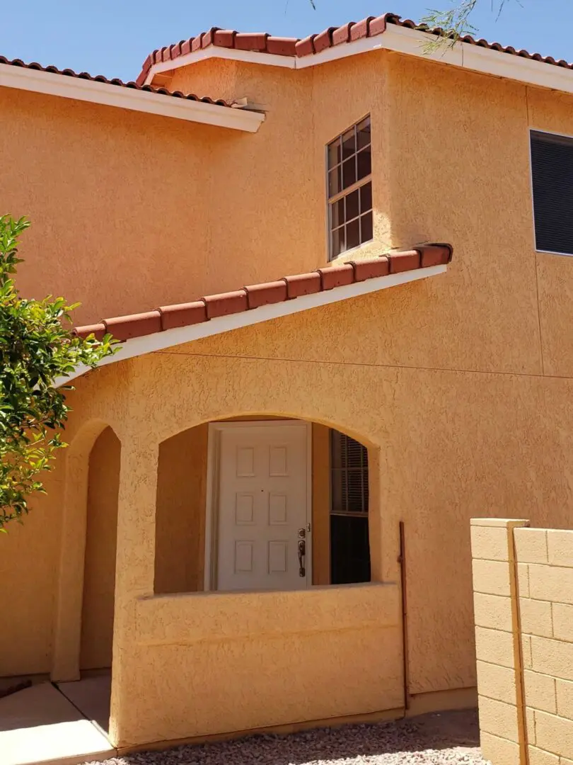 A tan house with a white door and window.