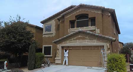 A man standing in front of a house with paint on the outside.